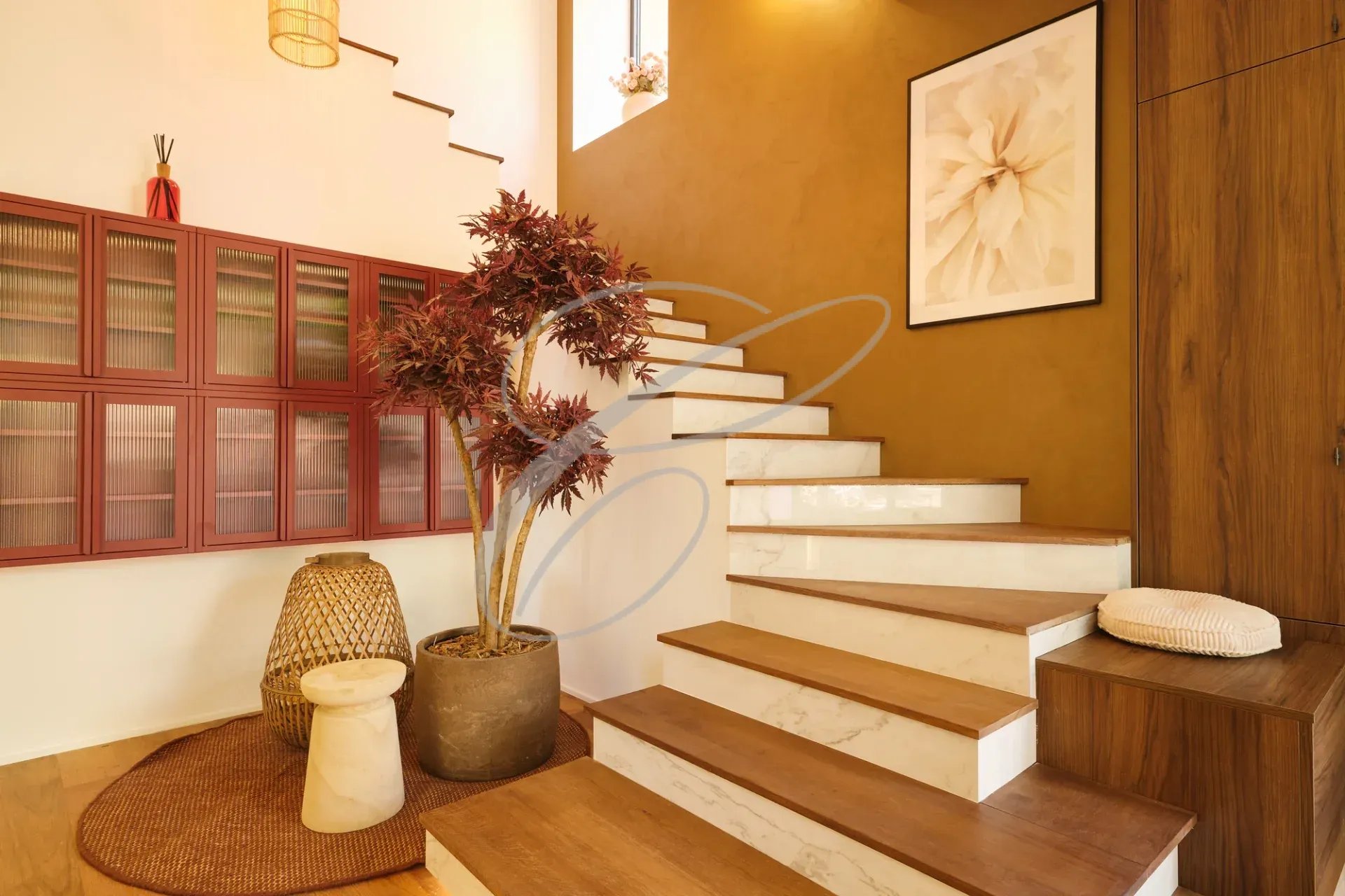 Escalier menant à l'étage d'une propriété rénovée avec décoration moderne et plante d'intérieur.