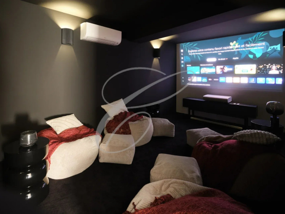 Salle de cinéma avec des poufs et un écran de projection dans une propriété rénovée.