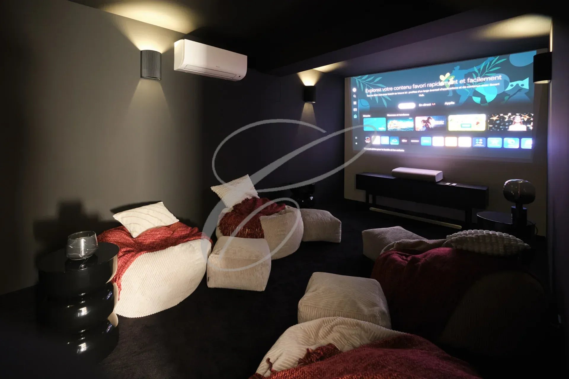 Salle de cinéma avec des poufs et un écran de projection dans une propriété rénovée.