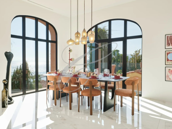 Salle à manger moderne avec vue sur la mer, grandes fenêtres et décoration élégante.