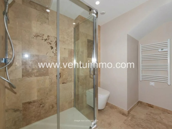 Modern bathroom with glass shower and stone tiles.