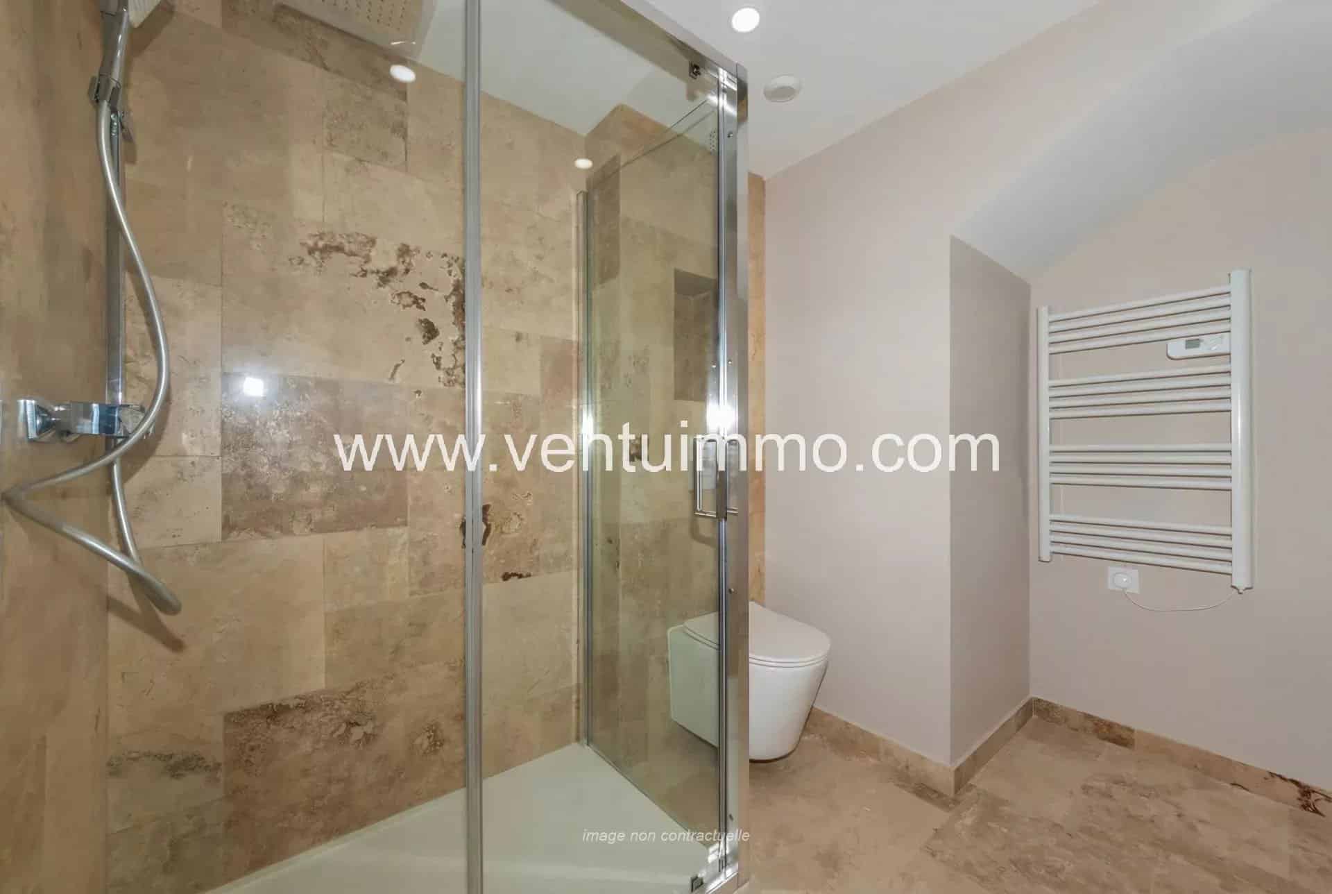 Modern bathroom with glass shower and stone tiles.