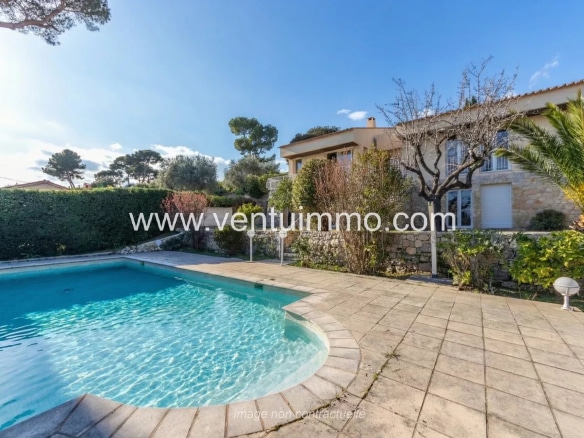 Swimming pool and terrace of a semi-detached house in Mougins, with a green garden.