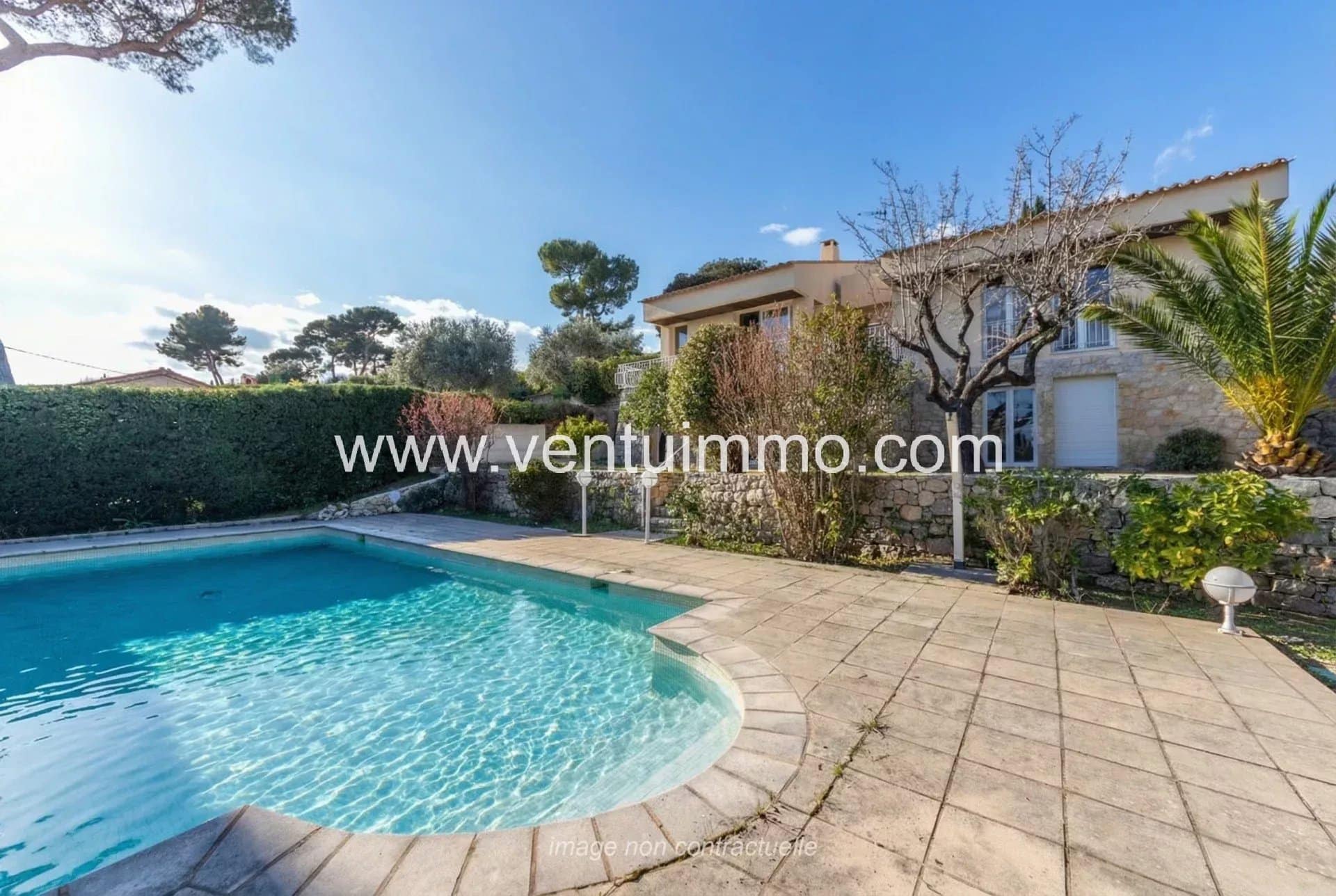 Swimming pool and terrace of a semi-detached house in Mougins, with a green garden.