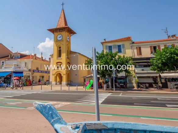 View of a building with a clock in Cagnes-sur-Mer, surrounded by shops and a busy street.