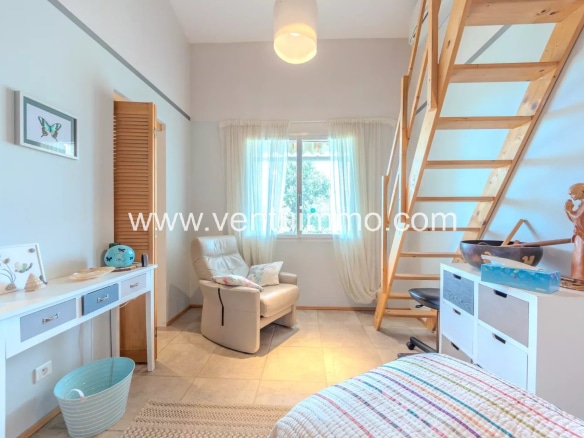 Intérieur d'une maison avec un coin salon et un escalier en bois.