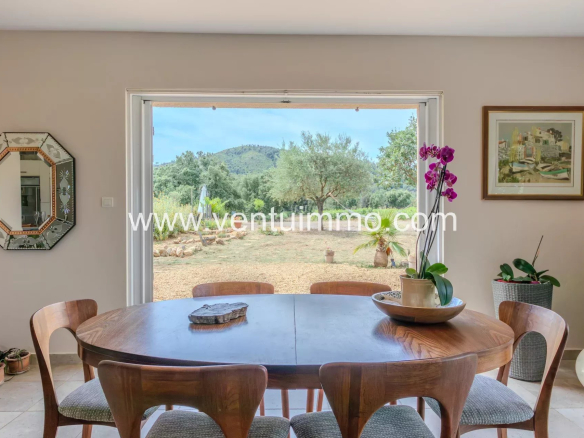 Intérieur d'une maison avec une table ronde et vue sur un jardin à La Garde-Freinet.