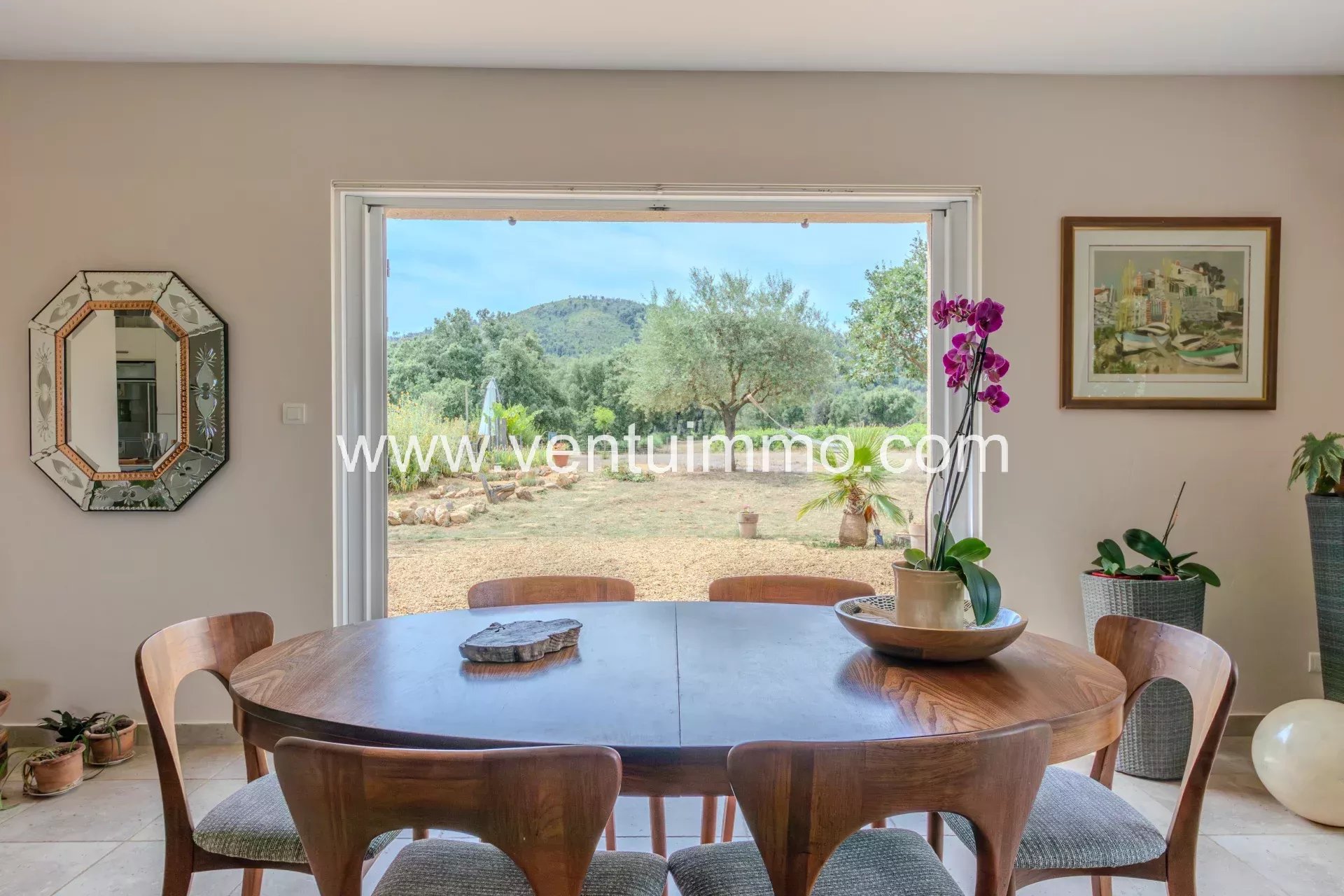 Intérieur d'une maison avec une table ronde et vue sur un jardin à La Garde-Freinet.