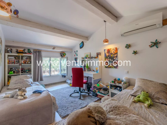 Bedroom in a house in La Garde-Freinet with two beds, desk and wall decorations.
