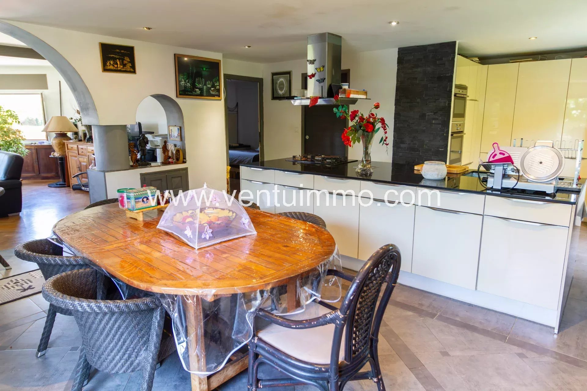 Cuisine moderne dans une propriété à Cagnes-sur-Mer Intérieur d'une cuisine moderne avec table en bois et chaises en rotin.