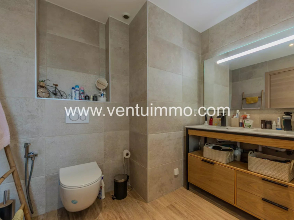 Salle de bain moderne avec carrelage beige et meuble en bois.