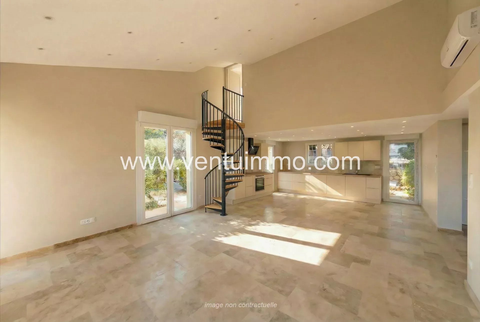 Intérieur d'une maison mitoyenne à Mougins, avec un escalier en colimaçon et un espace lumineux.