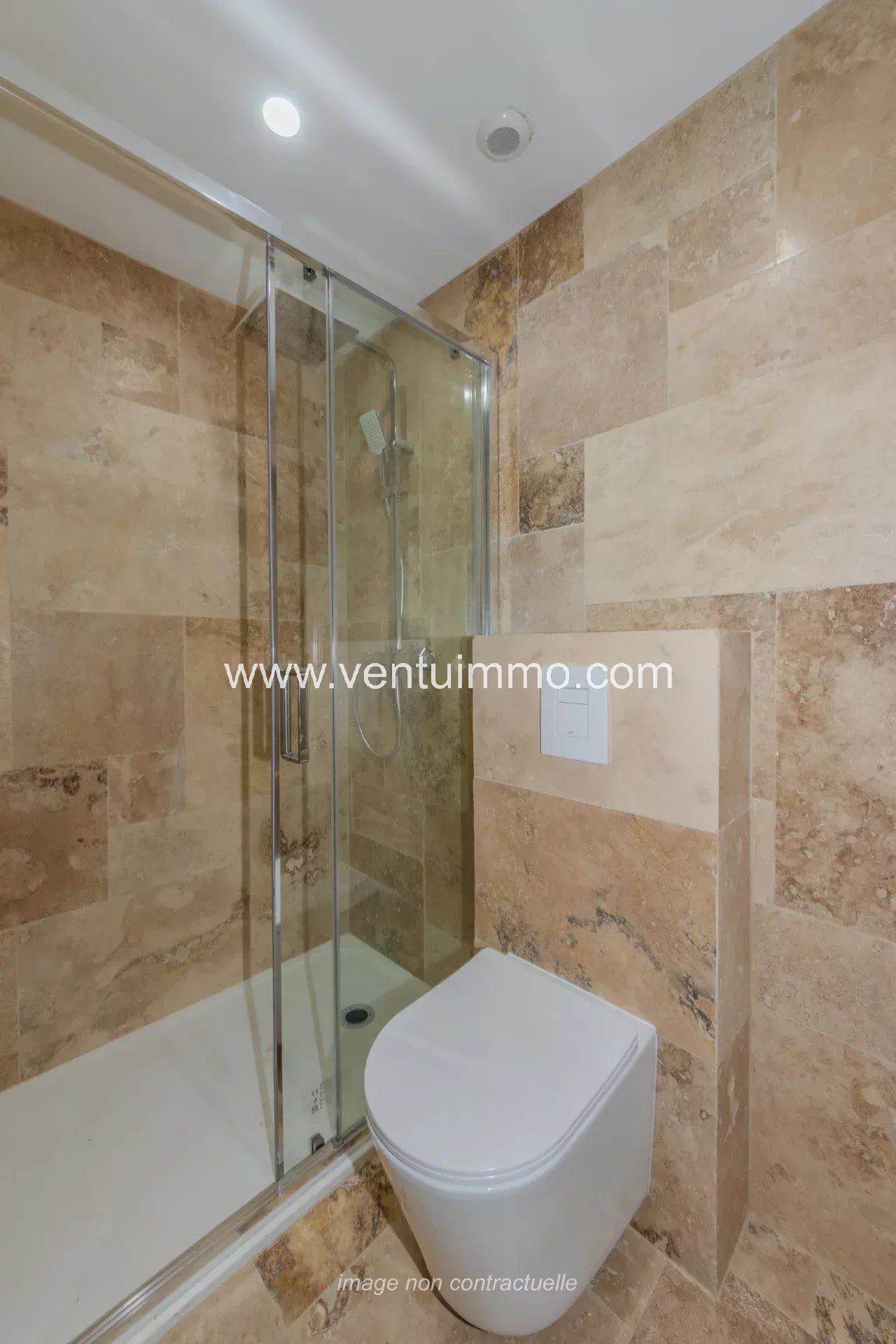 Salle de bain moderne avec douche et toilettes, carrelage en marbre.