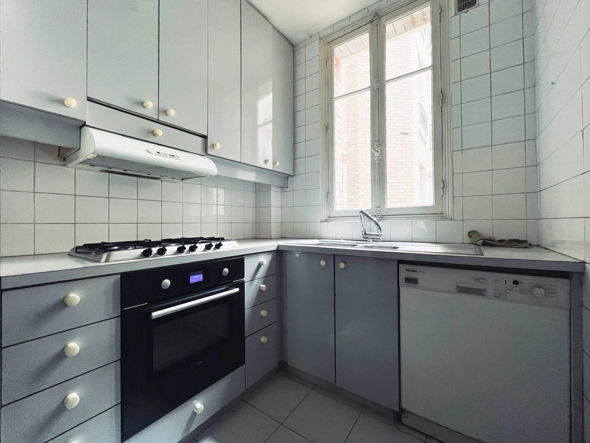 Cuisine d’un appartement familial à Neuilly-sur-Seine Cuisine d'un appartement à rénover avec meubles et équipements intégrés, fenêtres ouvertes sur l'extérieur.