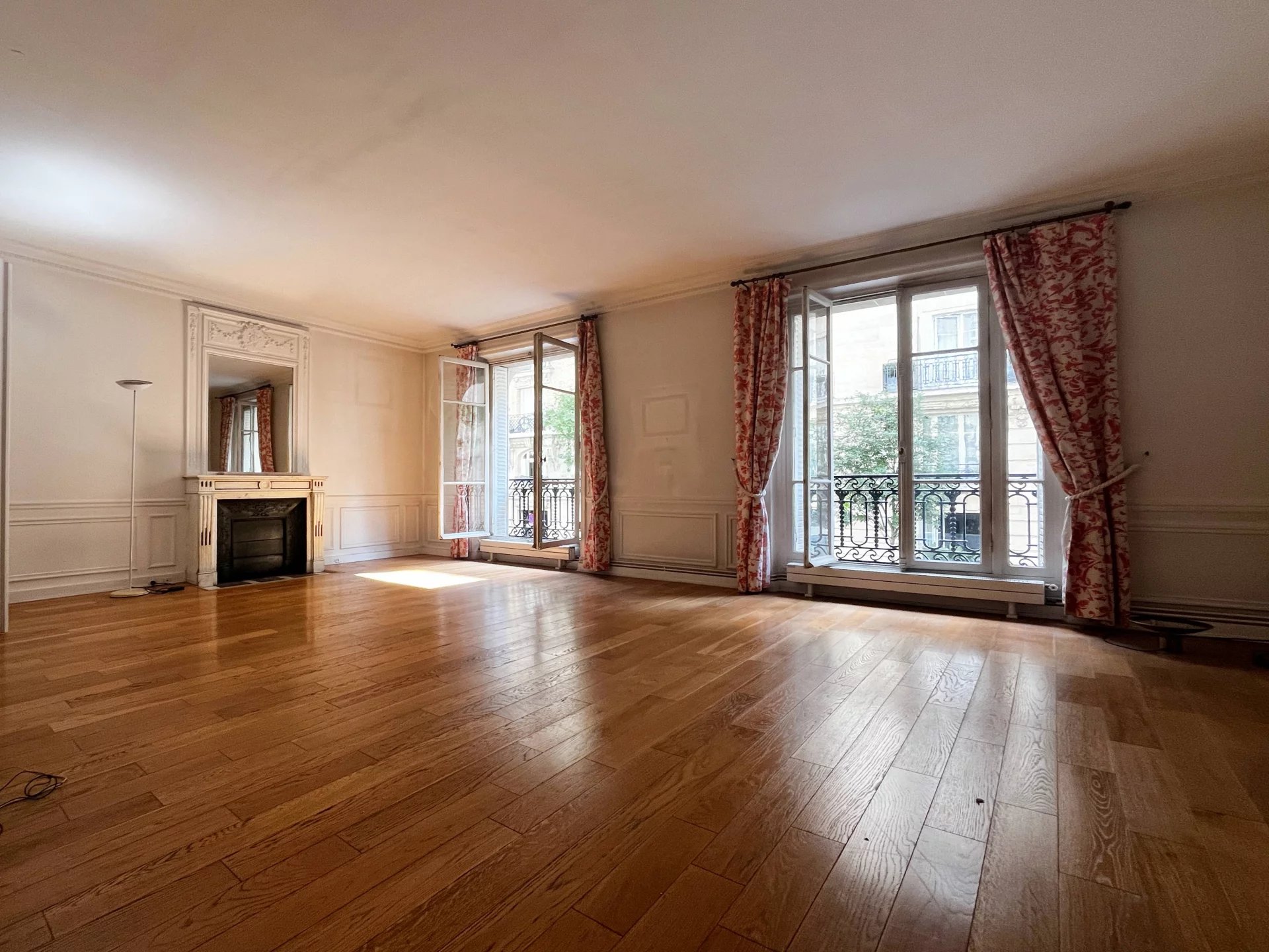 Appartement familial à rénover à Neuilly-sur-Seine Intérieur d'un appartement familial à rénover avec parquet et moulures, fenêtres donnant sur un balcon.