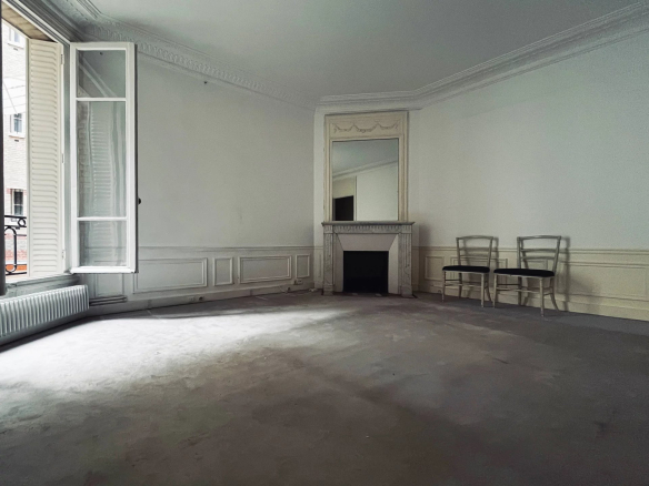 Intérieur d'un appartement à rénover avec murs clairs, parquet et fenêtres, situé à Neuilly-sur-Seine.