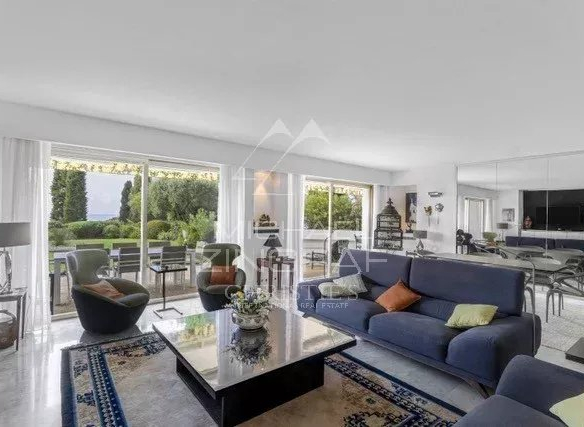 Salon lumineux d'un appartement avec vue sur un jardin, mobilier moderne et décor élégant.