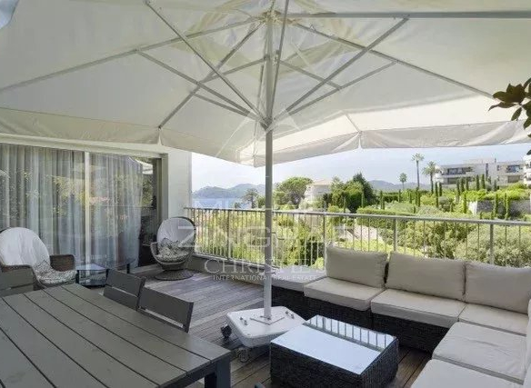 Terrasse d'un appartement avec mobilier extérieur et parasol, vue sur la nature à Cannes.