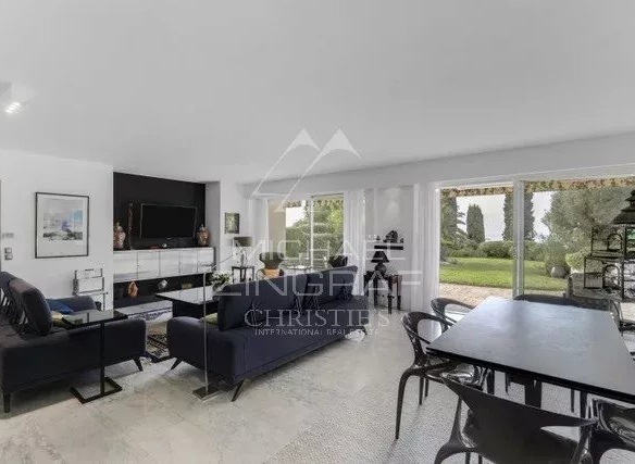 Intérieur d'un appartement moderne avec salon et salle à manger, accès à un jardin.