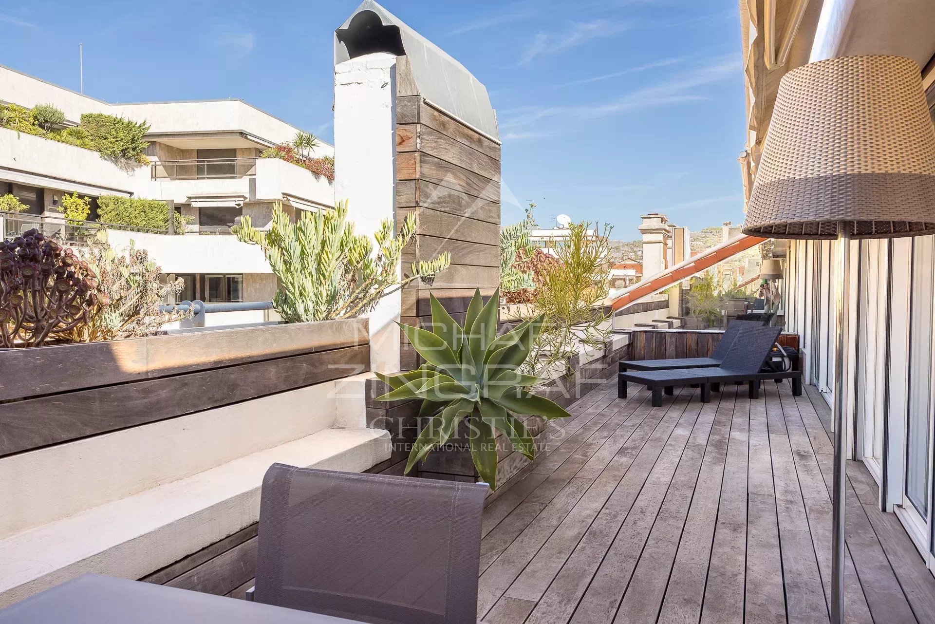 Terrasse en bois de 40 m² avec chaises longues et plantes, vue sur bâtiments à Cannes.