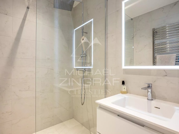 Salle de bain moderne avec douche à l'italienne et lavabo, murs en carrelage clair.