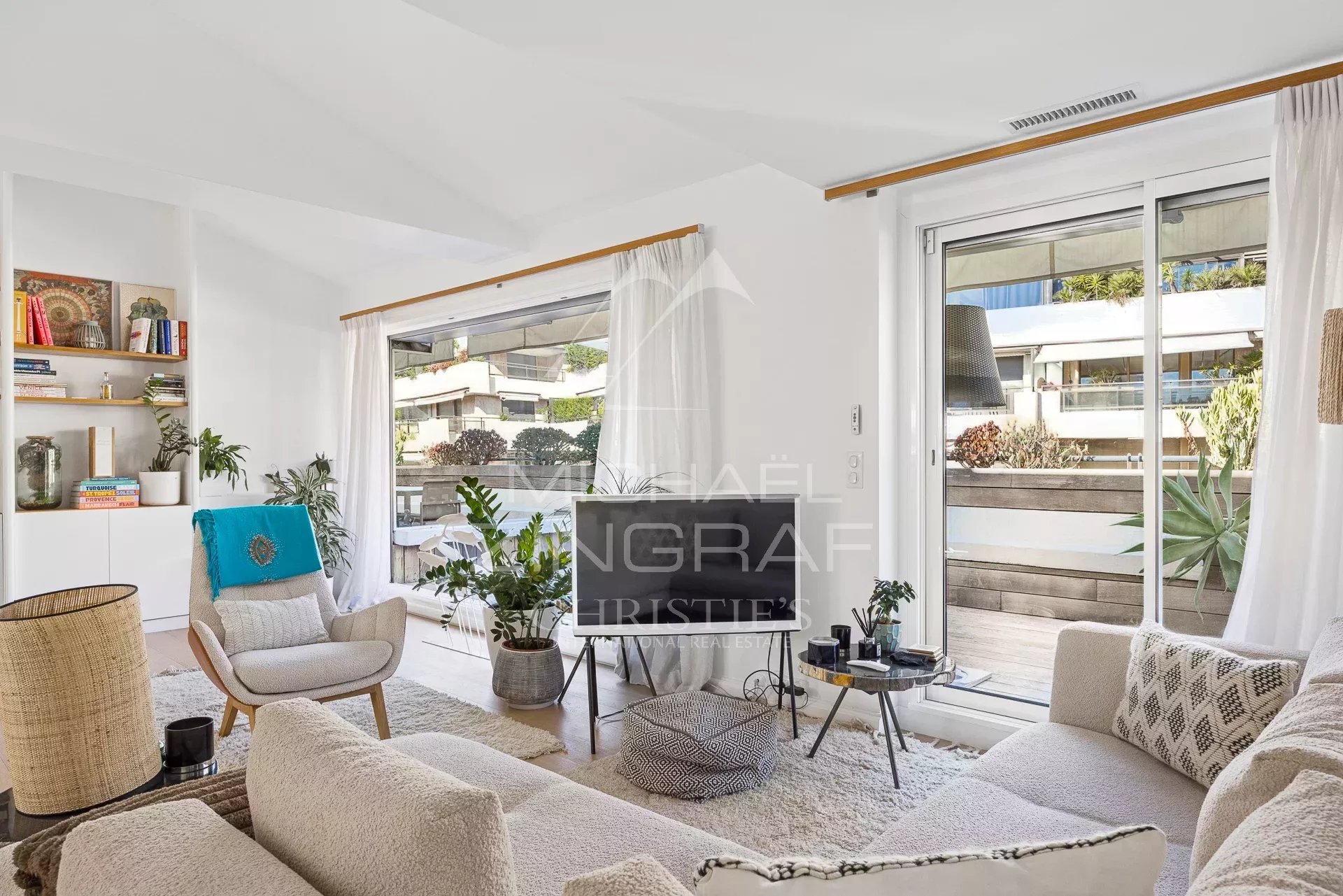 Salon lumineux d'un appartement à Cannes avec terrasse, décor moderne et plantes.