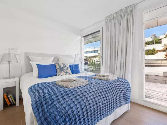Chambre d'un appartement moderne avec literie bleue et accès à une terrasse.
