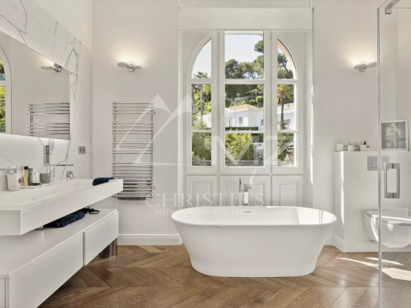 Modern bathroom with bathtub and arched window, abundant natural light.