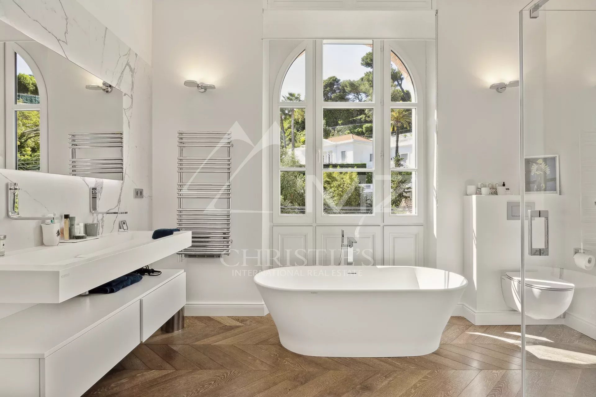 Modern bathroom with bathtub and arched window, abundant natural light.