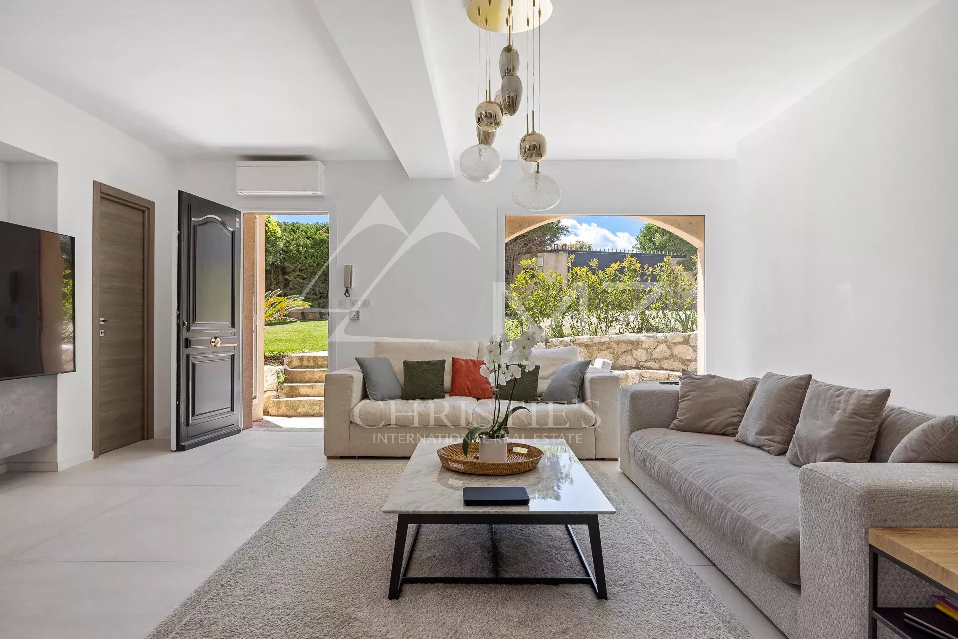 Modern living room with sofa and coffee table, overlooking a green garden in Vallauris.