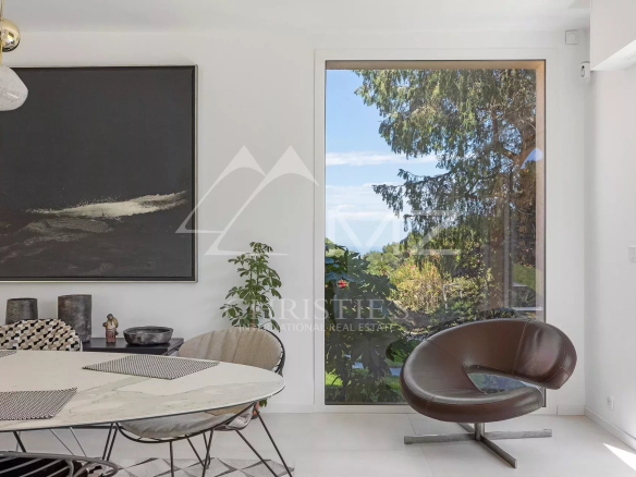 Interior of a modern house overlooking a green garden and blue sky.