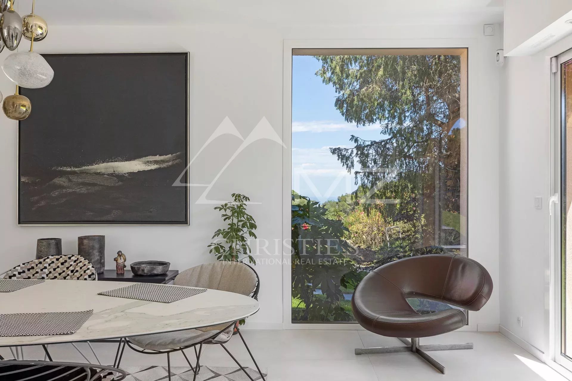 Interior of a modern house overlooking a green garden and blue sky.