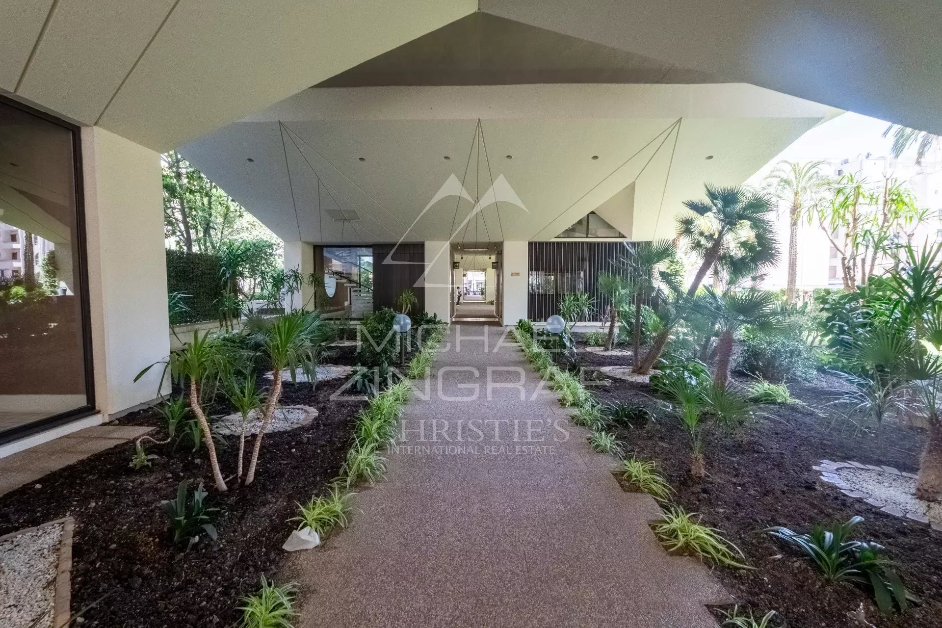 Entrance to a modern building with a landscaped garden in Cannes.