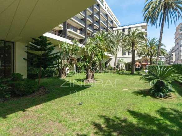 A lush garden with palm trees and modern buildings in Cannes