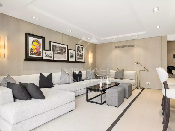 Modern living room of an apartment in Cannes, with light-colored sofas and artwork on the walls.