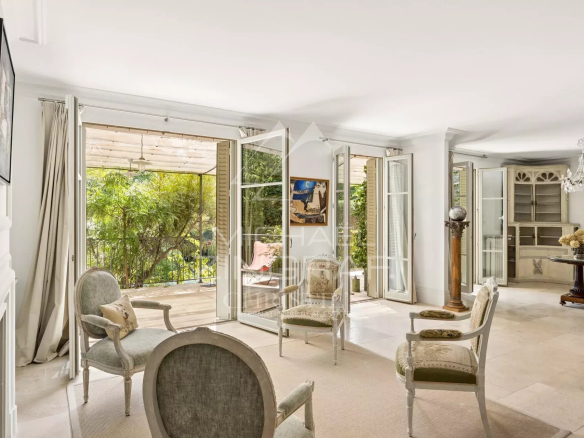Intérieur d'une maison élégante à Cannes avec salon lumineux et accès à une terrasse verdoyante.