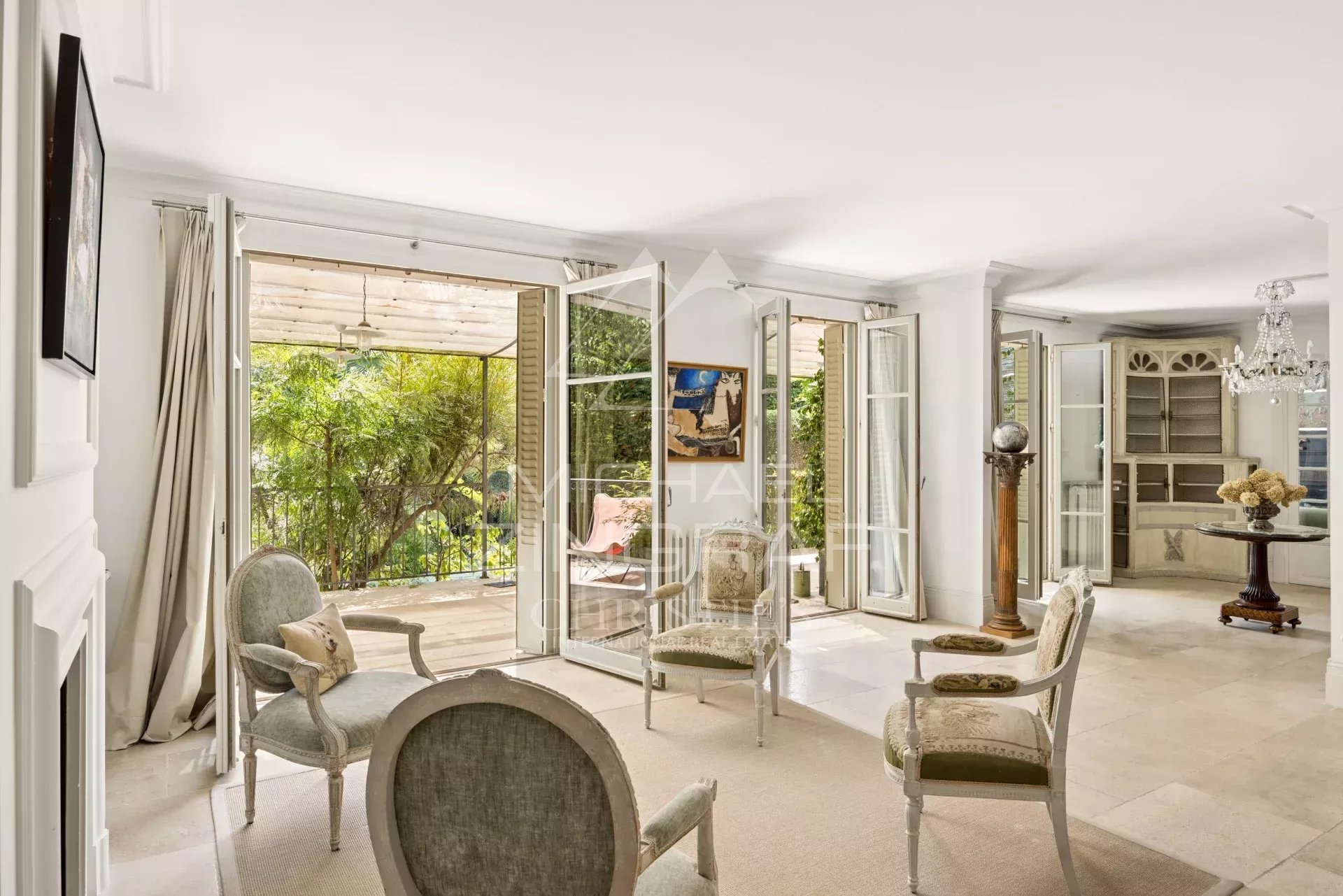Intérieur d'une maison élégante à Cannes avec salon lumineux et accès à une terrasse verdoyante.