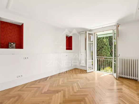 Intérieur d'une maison à Cannes avec parquet en bois et fenêtres ouvertes sur un jardin.