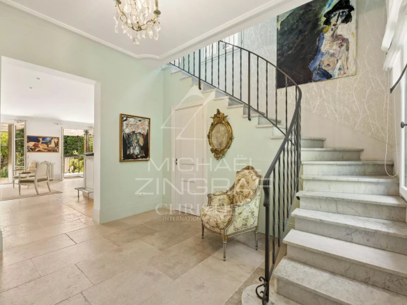 Intérieur d'une maison élégante avec un escalier en marbre et des œuvres d'art aux murs.
