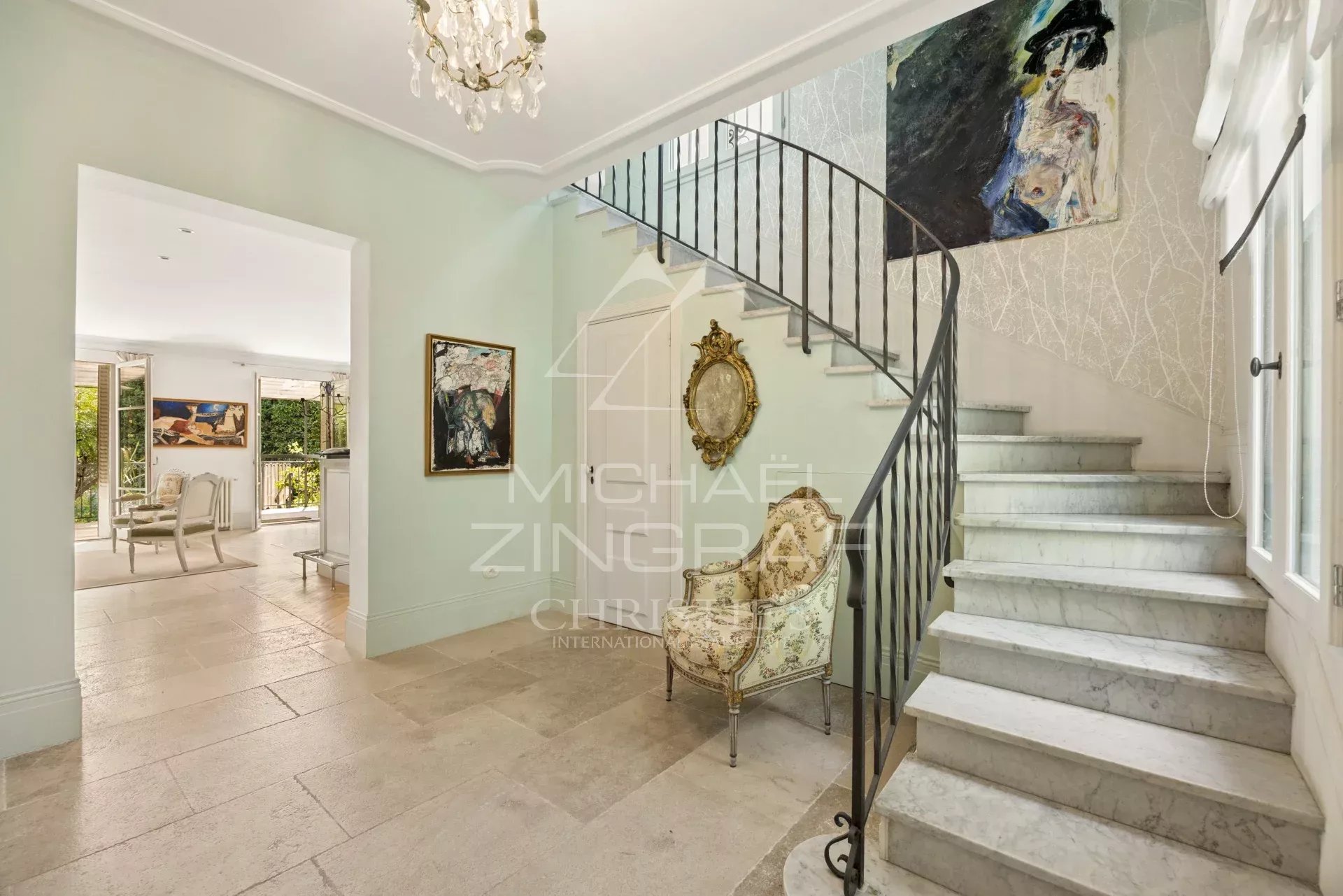 Intérieur d'une maison élégante avec un escalier en marbre et des œuvres d'art aux murs.