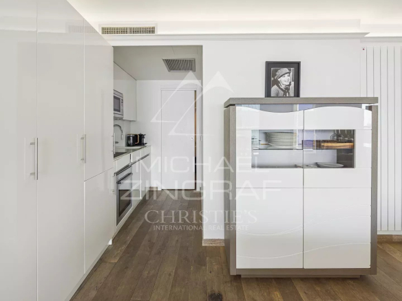 Cuisine moderne avec meubles blancs et espace de rangement, vue sur le séjour lumineux.