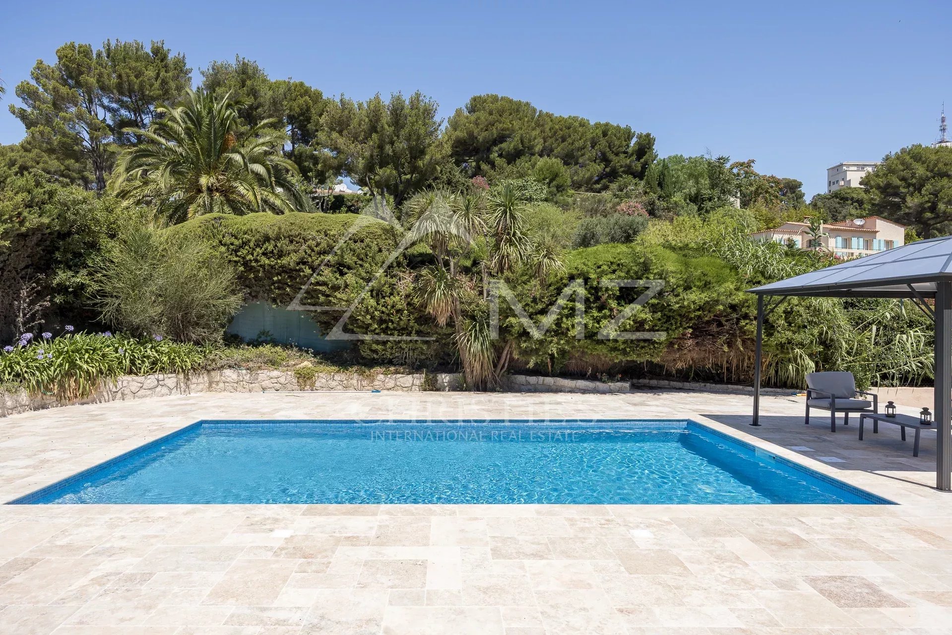 Swimming pool of a renovated family property in Vallauris, surrounded by greenery.