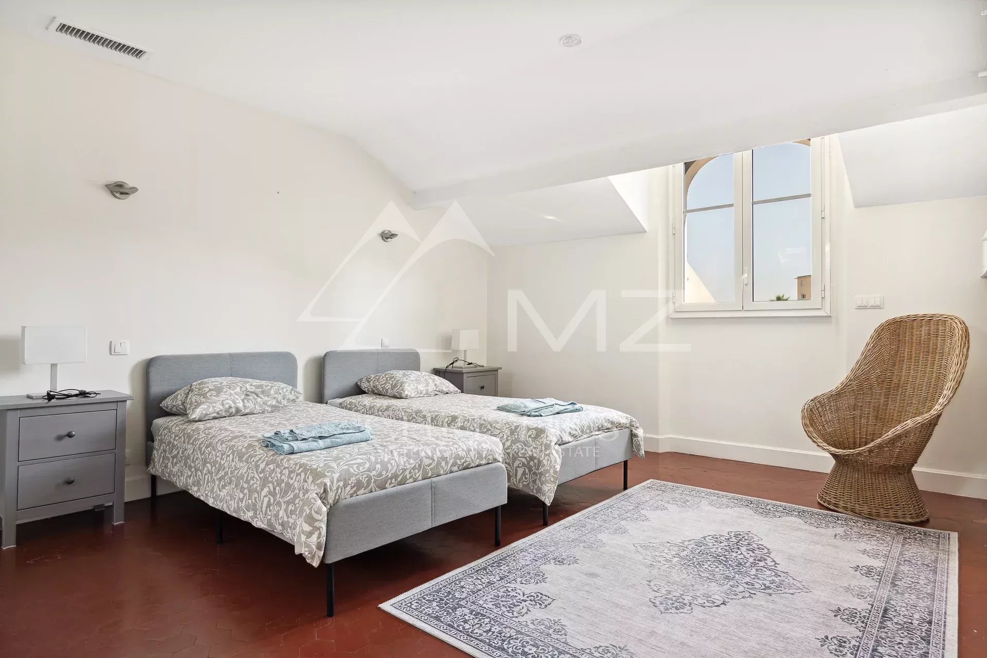 Chambre dans une villa bourgeoise à Cannes Chambre avec deux lits simples, fenêtre et fauteuil en osier, dans une villa bourgeoise à Cannes.