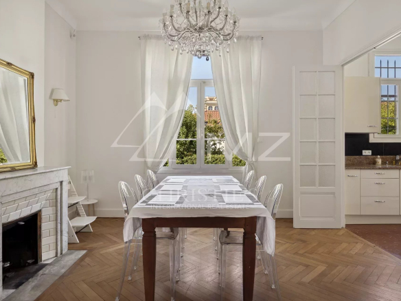 Intérieur d'une maison bourgeoise à Cannes, salle à manger lumineuse avec cheminée et table.