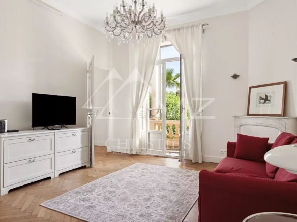 Intérieur d'une maison bourgeoise à Cannes, salon lumineux avec télévision et canapé rouge.