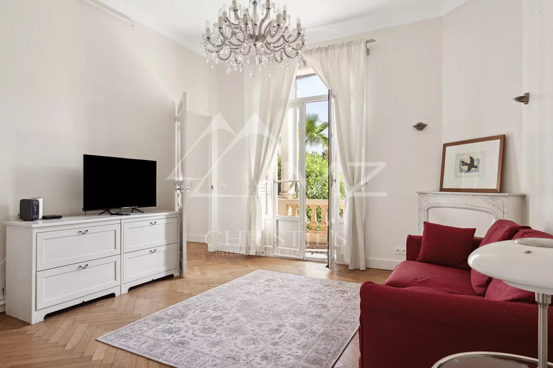 Salon d’une maison bourgeoise à Cannes Intérieur d'une maison bourgeoise à Cannes, salon lumineux avec télévision et canapé rouge.