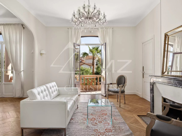 Intérieur d'une maison bourgeoise à Cannes, avec un salon lumineux et des fenêtres ouvertes sur l'extérieur.
