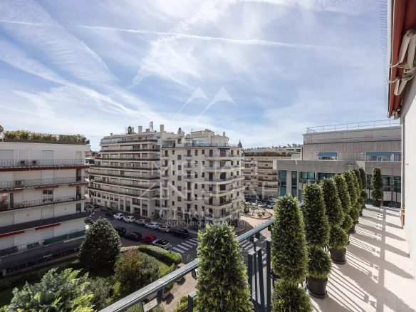 Vue depuis une terrasse d'un appartement à Cannes, montrant des bâtiments environnants et un ciel dégagé.