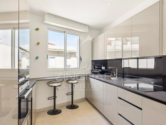 Cuisine moderne et équipée d'un appartement rénové à Cannes, avec bar et fenêtres lumineuses.