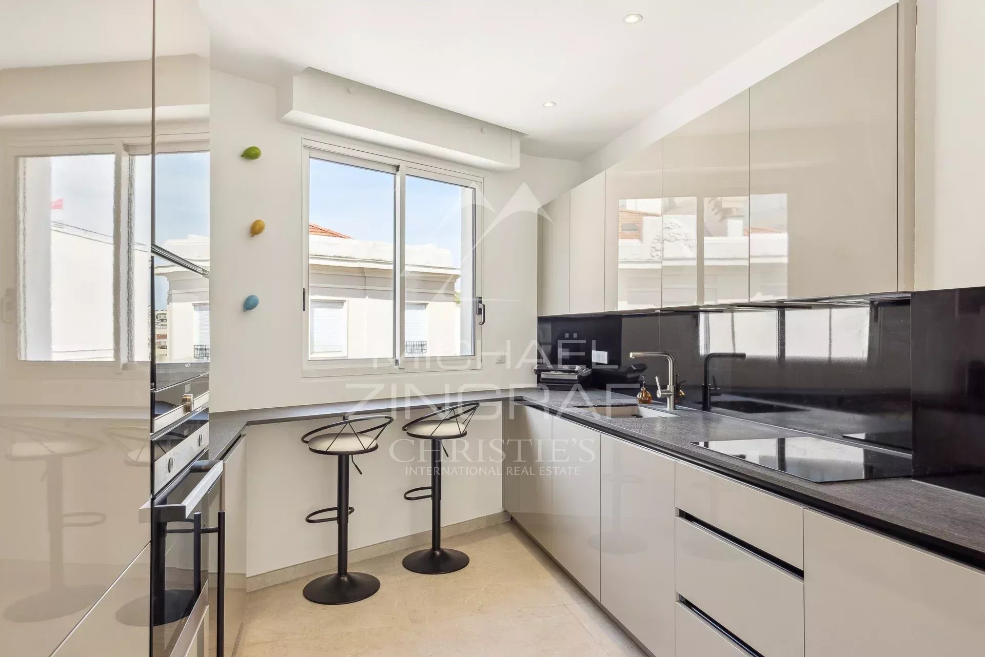 Cuisine d’un appartement rénové à Cannes Cuisine moderne et équipée d'un appartement rénové à Cannes, avec bar et fenêtres lumineuses.
